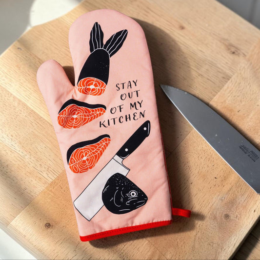 Mellow Monkey pink oven mitt with salmon slices, a knife, and fish head graphic. Features text "STAY OUT OF MY KITCHEN".