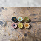 Mellow Monkey set of six colorful stoneware flower-shaped bowls with reactive glaze in various pastel and bold hues.