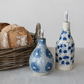 Mellow Monkey stoneware oil cruets in blue and white floral patterns with stainless steel spouts and plastic covers.