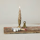 Mellow Monkey white stoneware tree-shaped match holder with striker next to a gold candle on a rustic wooden board.