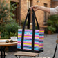 Mellow Monkey Original Deano small striped tote bag with black handles and base held by a hand in an outdoor cafe.