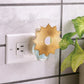Mellow Monkey Sunburst WallScents fragrance warmer in gold with a sun-shaped design plugged into a wall outlet.