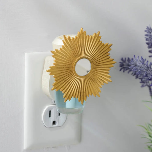 Mellow Monkey Sunburst WallScents fragrance warmer with a gold sunburst design plugged into a wall outlet.
