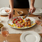 Mellow Monkey 18-inch ceramic oval platter featuring a vibrant sunflower pattern, served with appetizers on a table.