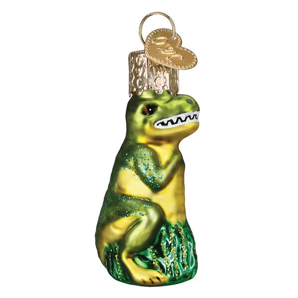 Mellow Monkey Mini T-Rex blown glass holiday ornament, green and yellow with glitter accents, sitting on green grass.