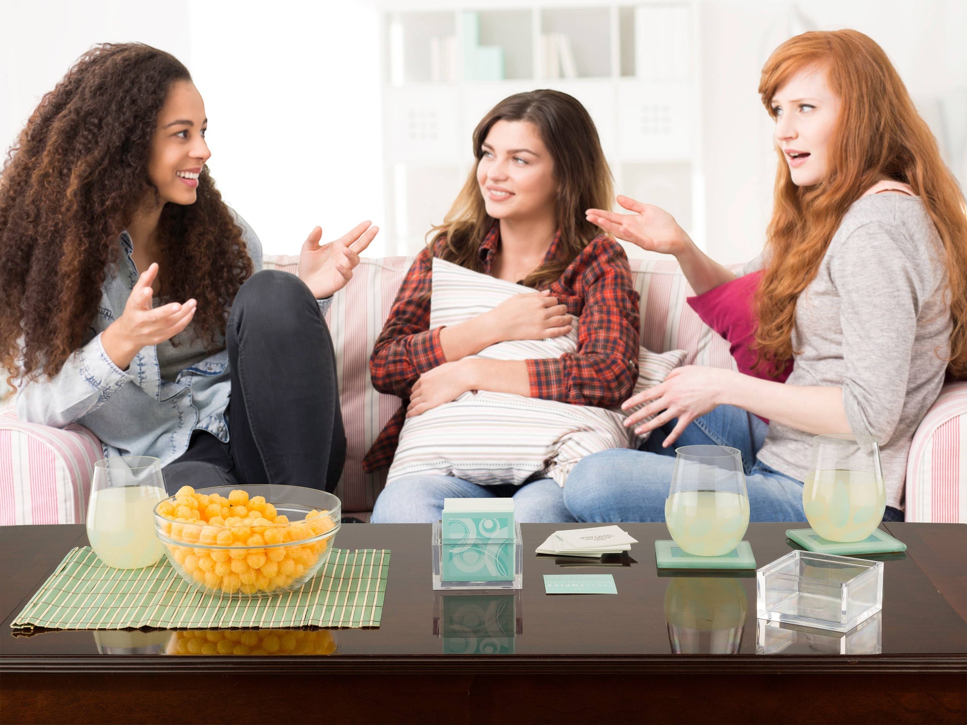 Mellow Monkey TABLETOPICS TEEN conversation cards in an acrylic cube on a coffee table with three teenage girls