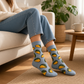 Mellow Monkey bamboo knit socks in grey with a golden-yellow taco pattern worn by a person sitting on a sofa