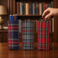 Mellow Monkey tartan plaid triangular weighted eyeglass holders in three different fabric patterns on a wooden desk.