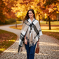 Mellow Monkey Alora taupe plaid wrap with fringed edges and front loop closure worn by a woman in an autumn park