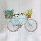 Mellow Monkey teal bicycle with baskets of crabs and corn on a white cotton flour sack towel.