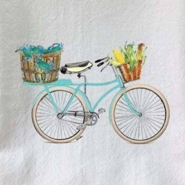 Mellow Monkey teal bicycle with baskets of crabs and corn on a white cotton flour sack towel.