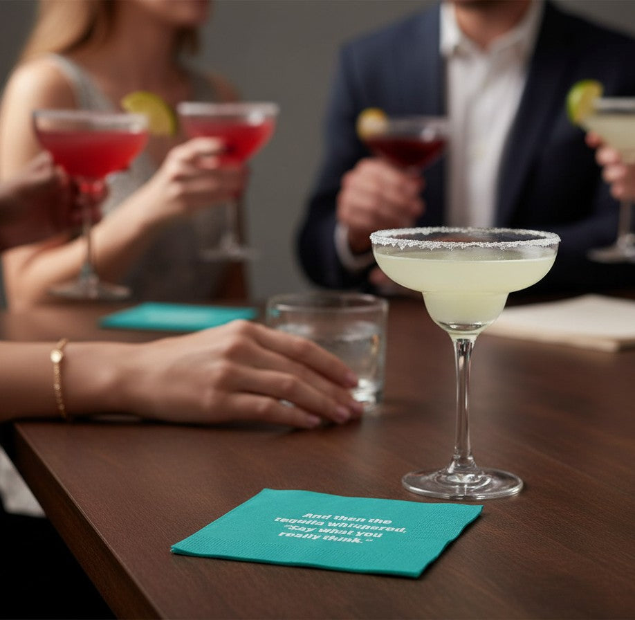 Mellow Monkey teal cocktail napkin with white text saying And then the tequila whispered on a table with drinks