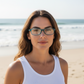 Mellow Monkey teal pocket reading glasses worn by a woman on a sunny beach