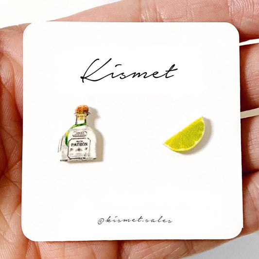 Mellow Monkey handmade Tequila bottle and lime wedge stud earrings on a white display card held in a hand.