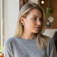 Mellow Monkey handmade Tequila and Lime stud earrings worn by a woman in a grey sweater sitting in a cafe.