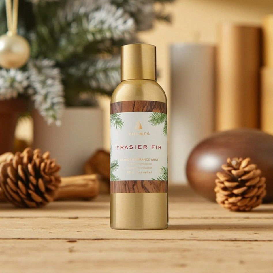 Mellow Monkey Thymes Frasier Fir home fragrance mist in a gold bottle with wood grain label on a rustic wooden table.