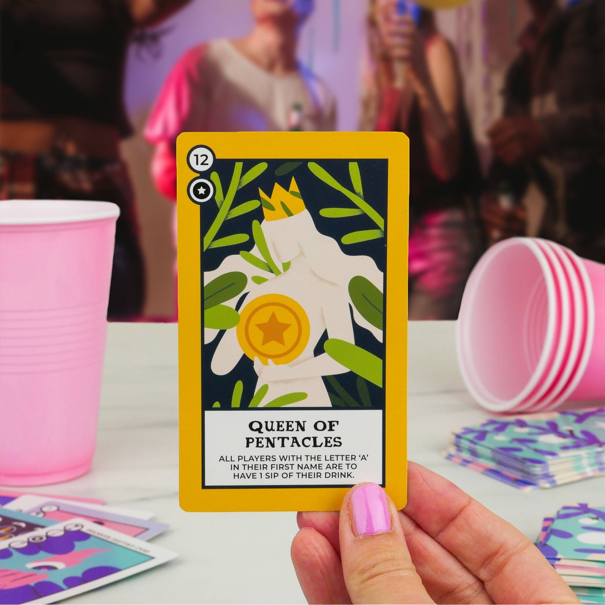 Mellow Monkey Tipsy Tarot Queen of Pentacles drinking game card held in hand with pink party cups in background