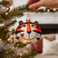 Mellow Monkey Tony the Tiger glass Christmas ornament hanging on a decorated tree with a hand holding the gold loop