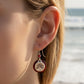 Mellow Monkey SV Round Tree of Life earrings featuring a silver tree motif on a deep red disc worn by a woman at beach