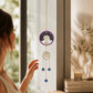 Mellow Monkey Tree of Life suncatcher with purple healing stones and gold chains hanging in a sunlit window.