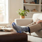 Mellow Monkey Trophy Husband gray socks with navy blue accents, featuring a trophy graphic, worn by a man relaxing.