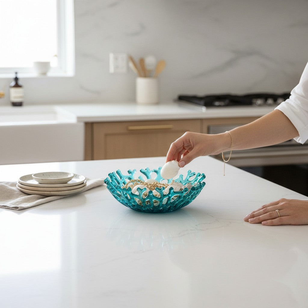 Mellow Monkey handmade turquoise glass coral bowl holding seashells on a white kitchen countertop