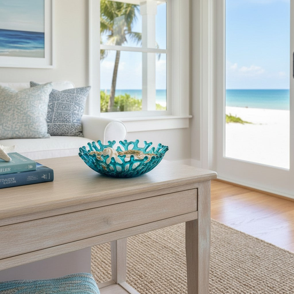 Mellow Monkey handmade turquoise glass coral bowl filled with seashells on a wooden coffee table in a beach house.