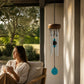 Mellow Monkey mini turquoise healing chime with aluminum tubes and wooden canopy hanging on a porch