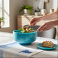 Mellow Monkey large turquoise and blue resin bowl with base being used to serve a fresh salad on a dining table.