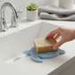 Mellow Monkey sea turtle shaped blue bioplastic soap lift pad under a bar of soap on a white bathroom sink