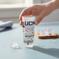 Mellow Monkey Catstudio University of Connecticut 2-oz frosted glass shot glass held by a hand on a blue table