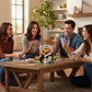 Mellow Monkey UNO Dare card game box on a wooden table with a group of friends laughing and playing in a living room.