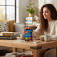 Mellow Monkey Harry Potter UNO card game box on a wooden table with a smiling woman playing in a cozy living room