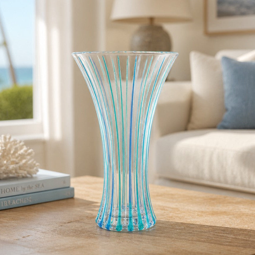 Mellow Monkey 12-inch Venetian glass fluted vase in aqua and blue stripes on a wooden table in a coastal living room.