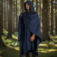 Man wearing a navy blue Mellow Monkey medieval Viking cloak with a hooded design in a forest setting.