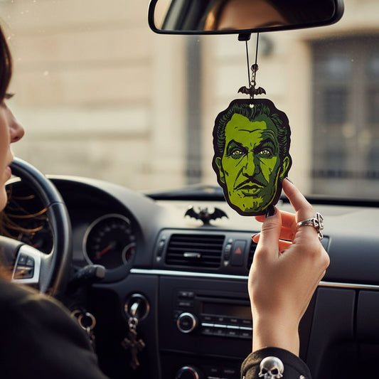 Mellow Monkey Vincent Price glow-in-the-dark air freshener hanging from a car rearview mirror with bat charm.