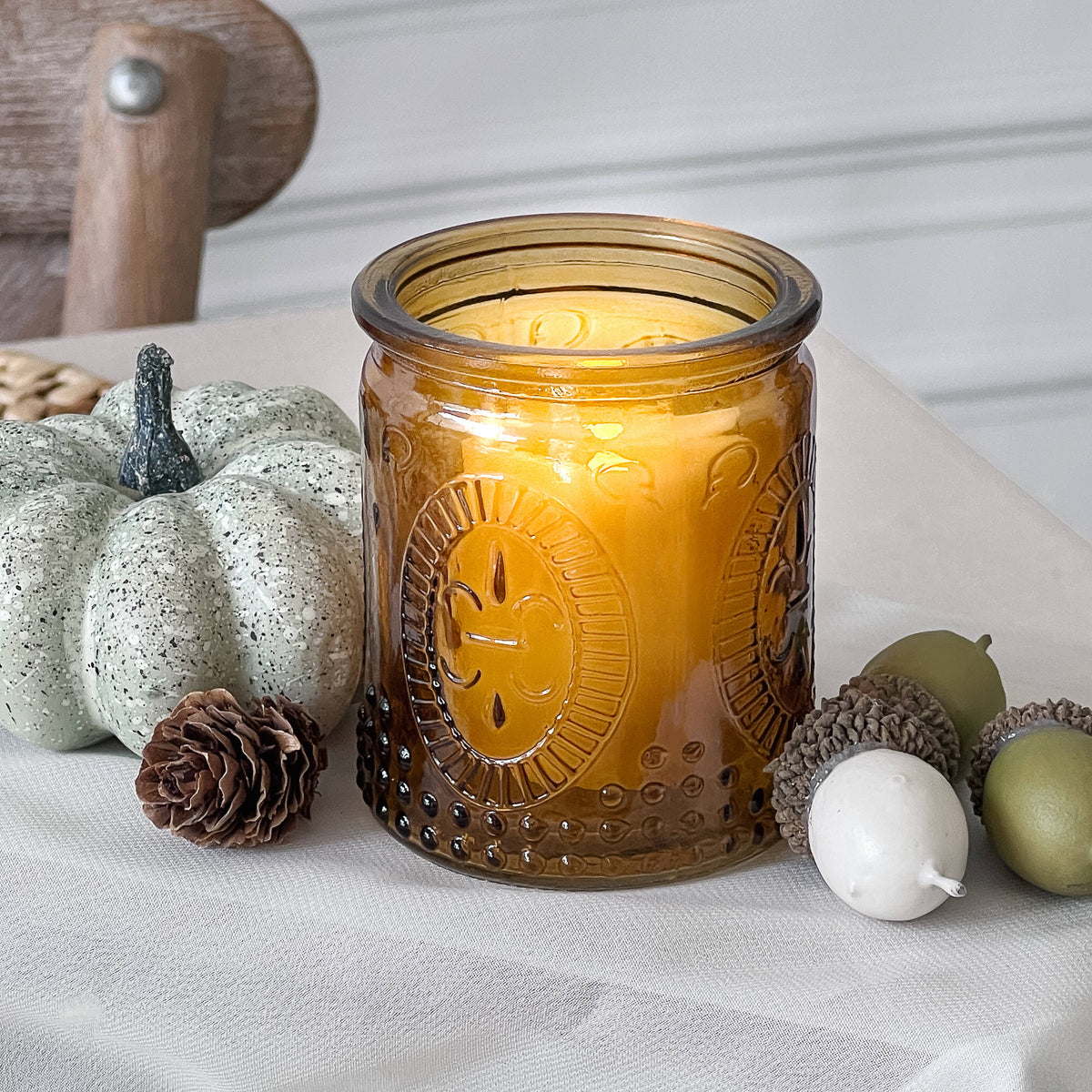 Mellow Monkey set of 4 vintage amber glass tea light holders with embossed fleur-de-lis pattern and warm candle glow.