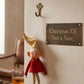 Mellow Monkey vintage-style elf ornament with gold hat and red outfit hanging next to a Christmas Elf sign