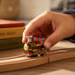 Mellow Monkey vintage style wind-up tin locomotive train toy on wooden tracks held by a child's hand