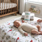 Mellow Monkey Virginia floral muslin swaddle blanket with cardinal print under a sleeping baby in a nursery.