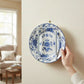 Mellow Monkey wall mount plate hanger holding a decorative blue and white floral plate on a beige wall.