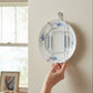 Mellow Monkey wall mountable plate hanger holding a decorative floral plate on a beige wall