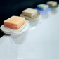 Mellow Monkey white waterfall soap dish with Soap Lift pad holding a bar of orange soap on a bathroom counter