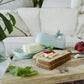 Mellow Monkey aqua ceramic whale butter dish with lid, tail handle, and wave rim detail. Holds butter stick.