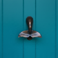 Mellow Monkey whale tail door knocker in oiled bronze mounted on a teal blue door