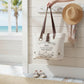 Mellow Monkey white canvas and leather crossbody tote bag with vintage French wine label print hanging on a wall hook