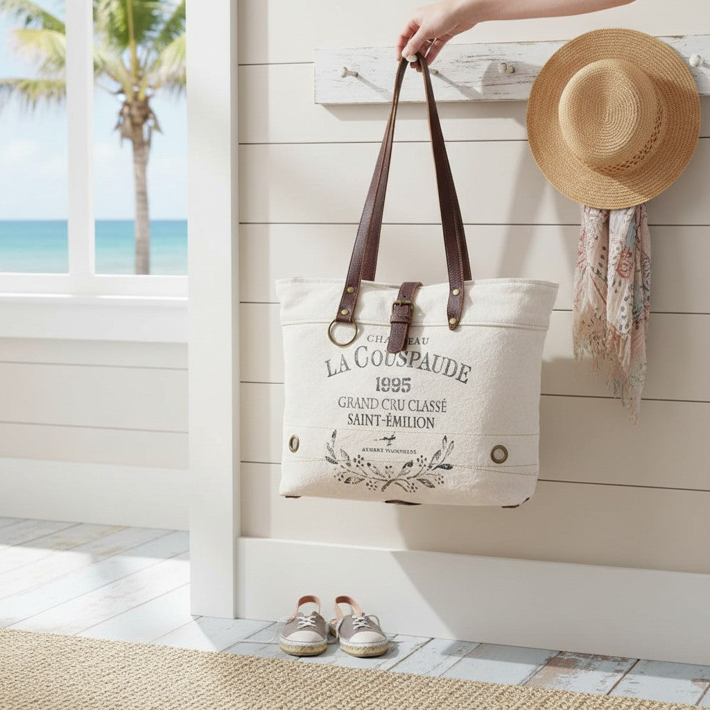 Mellow Monkey white canvas and leather crossbody tote bag with vintage French wine label print hanging on a wall hook