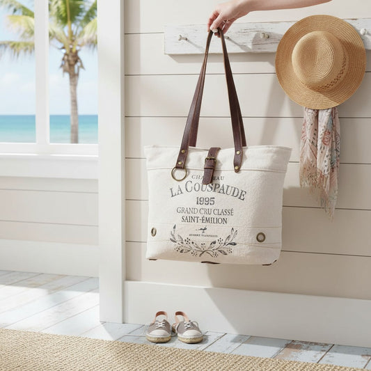 Mellow Monkey white canvas and leather crossbody tote bag with vintage French wine label print hanging on a wall hook