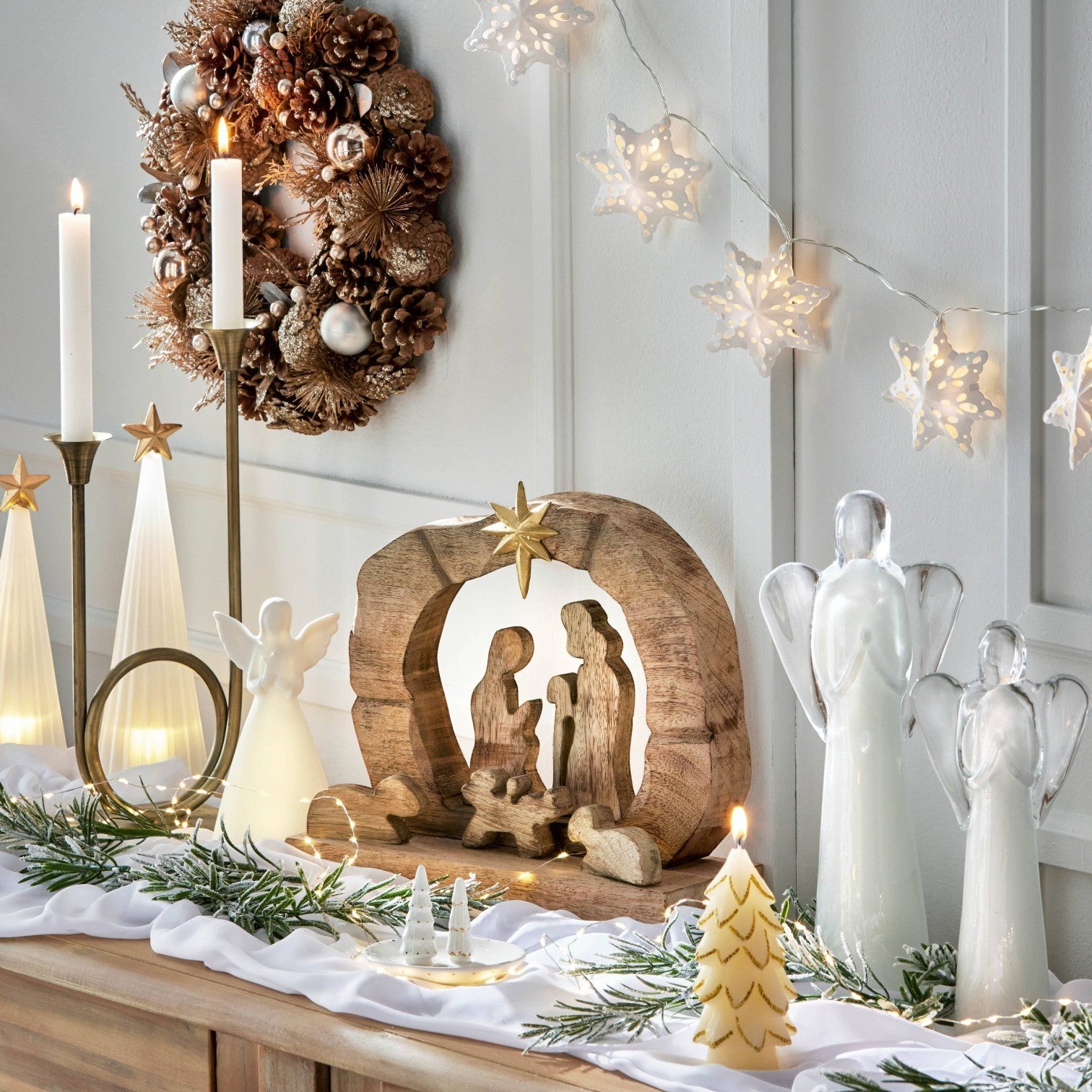Mellow Monkey white ceramic angel LED decor holding a star on a festive mantelpiece with holiday decorations.