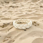 Mellow Monkey white cotton cord sailor knot bracelet resting on sandy beach